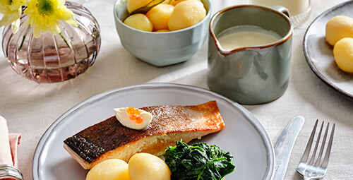 Pommes de terre confites au beurre avec saumon frit, crème fraîche, épinards et sauce au beurre