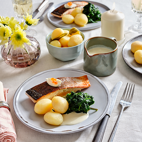 Pommes de terre confites au beurre avec saumon frit, crème fraîche, épinards et sauce au beurre